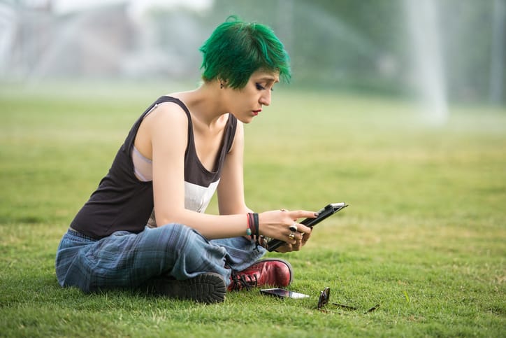 green haired woman sitting in the park