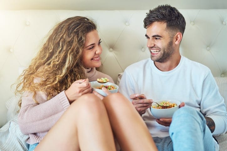 couple sitting in bed eating breakfast