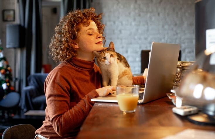 woman with laptop sand cat on table