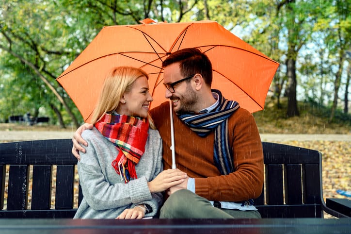 Couple sitting under umbrella in nature.