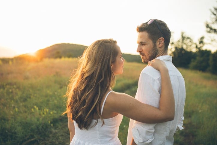 couple being intimate outside in the sunset