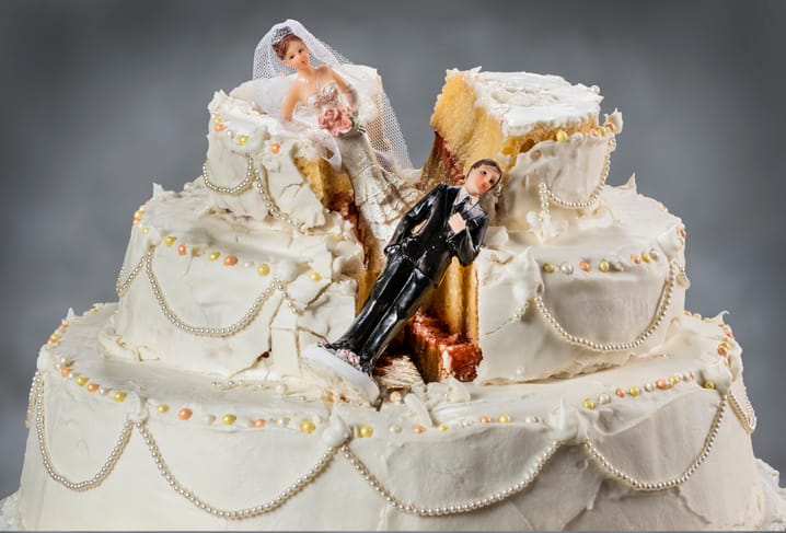 Bride and groom figurines collapsed on a ruined wedding cake.