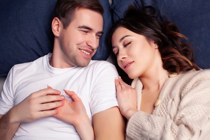 couple laid in bed smiling