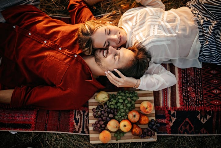 Man and woman laying outside on a picnic.