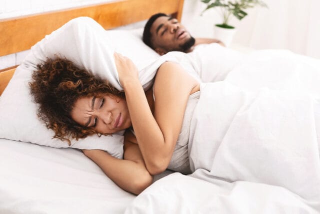 woman covering ears from snoring