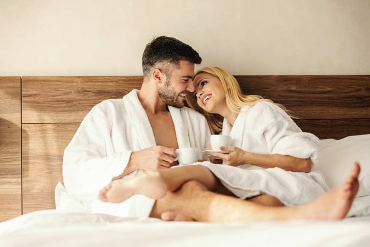 Couple laying in bed together in a hotel.