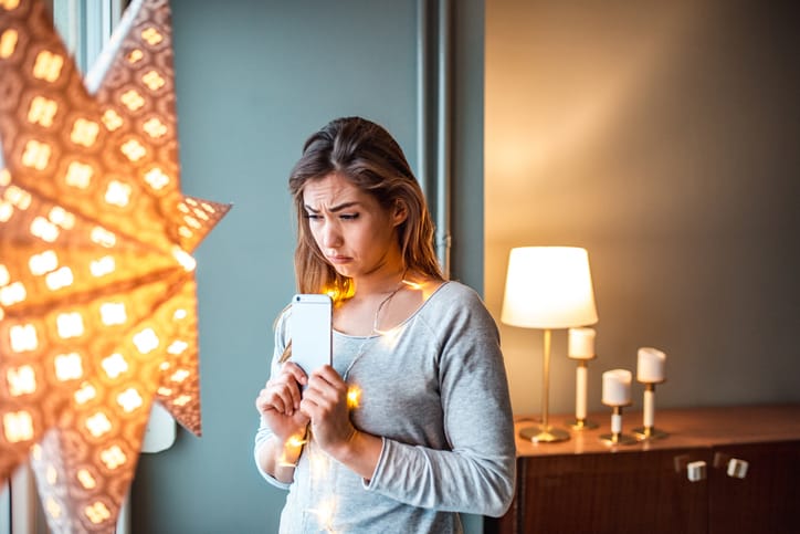 Young woman at home standing next to window