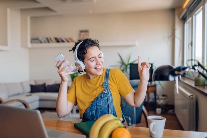 A woman dancing in the kitchen wearing headphones.