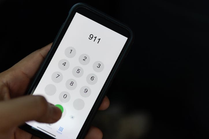 Hand holding cell phone with emergency number 911.
