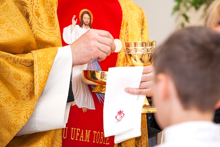 Priest gives child communion.