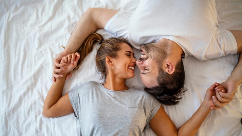 top view couple holding hands in bed