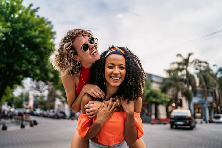 two female friends piggy back