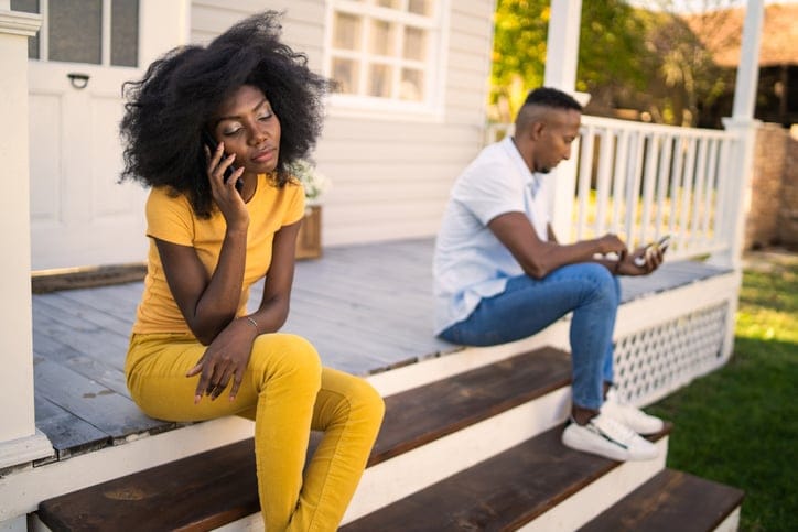 Unhappy couple sitting apart on a front porch.