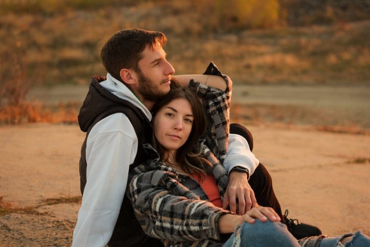 needy men relationshipClose up portrait of two lovers at dusk. Couple sit on the ground and hug, greet the sunset together.