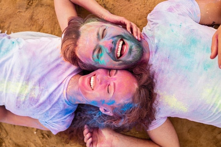 Couple laying on the floor covered in paint.