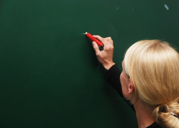 Female teacher writing on the blackboard.