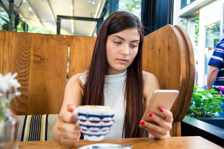 woman texting drinking coffee