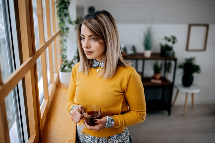 woman looking out window in yellow top