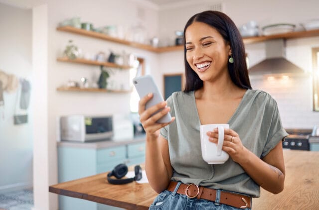 smiling woman texting in kitchen