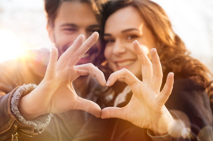 Man and woman making the heart hands.