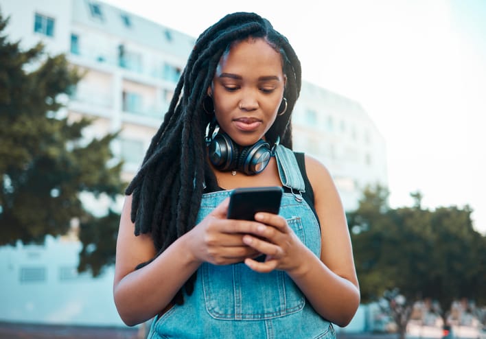 Woman texting on city street.