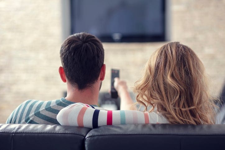 Couple relaxing and watching TV at home.