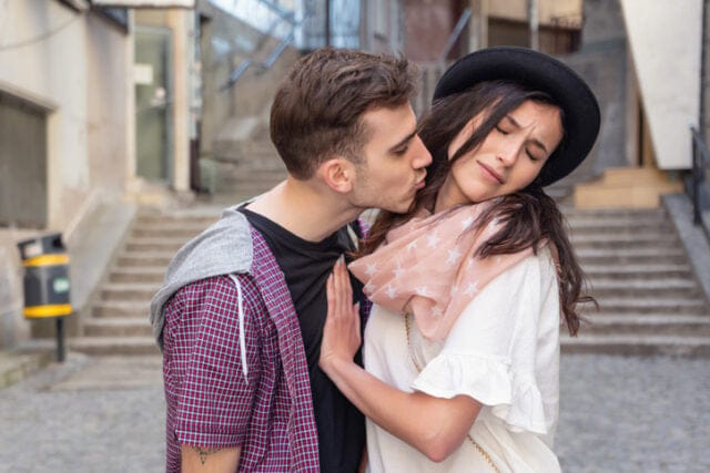 woman pushing man's kisses away