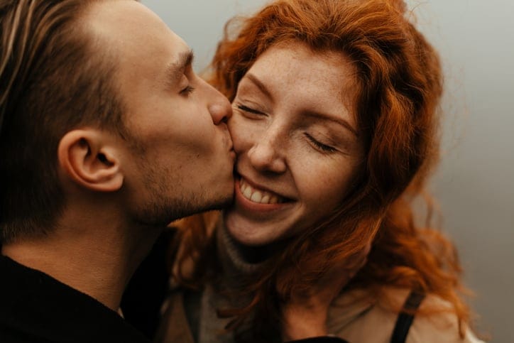 man kissing woman on cheek