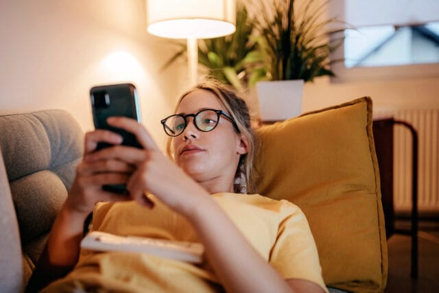 woman laying on couch texting