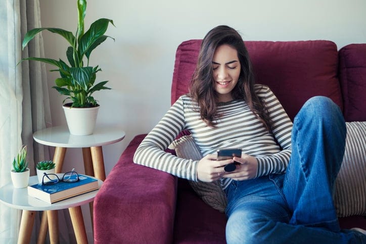 woman texting sitting on couch