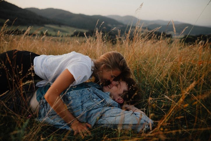 couple kissing outdoors in field