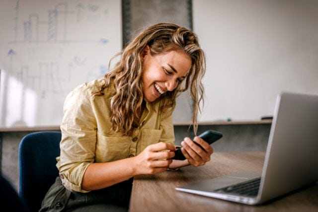 woman smiling while texting