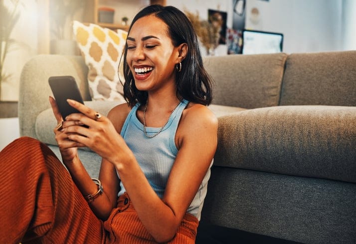 smiling woman texting on living room floor