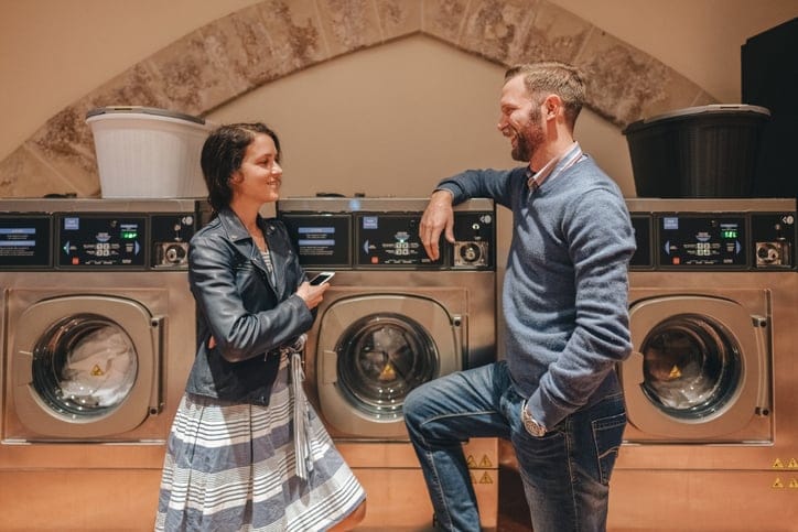 Young couple chatting at a laundromat.
