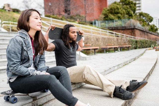 Skateboarding couple sitting on steps.