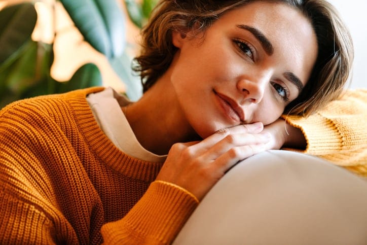 smiling brunette woman orange sweater