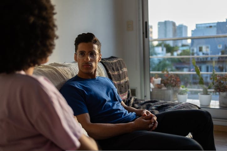 man and woman having convo on couch