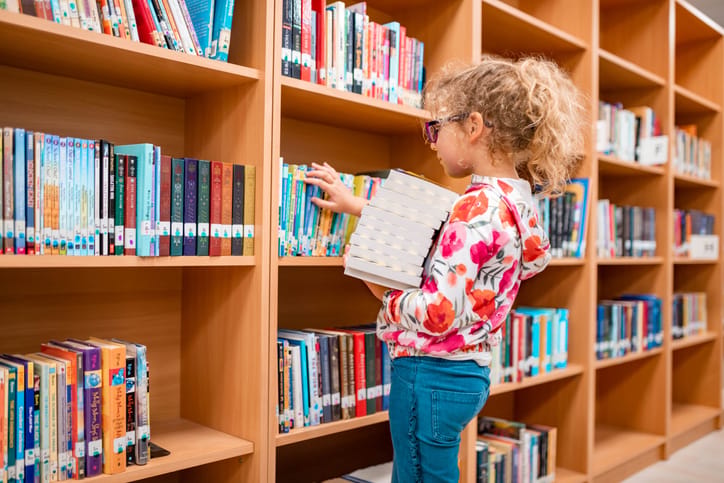 Little girl gathering library books.