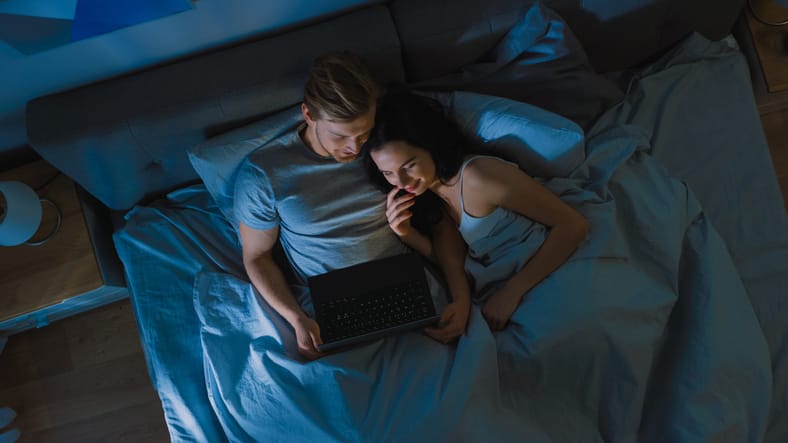 couple watching laptop in bed