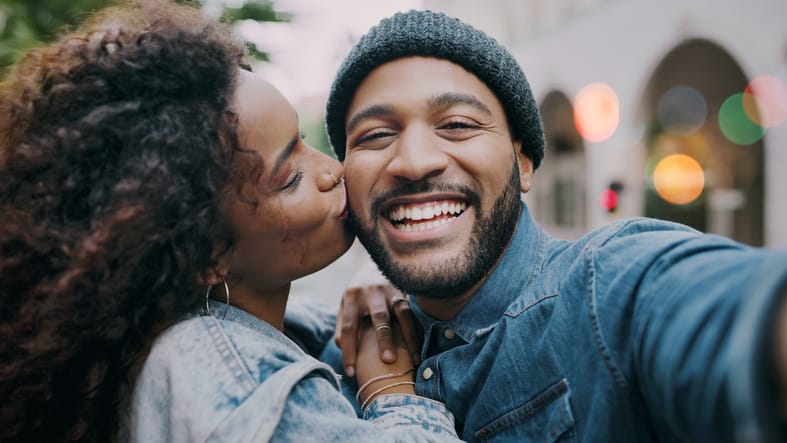 woman kissing smiling boyfriend on cheek