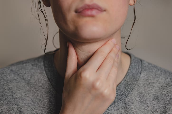 woman with hand on throat
