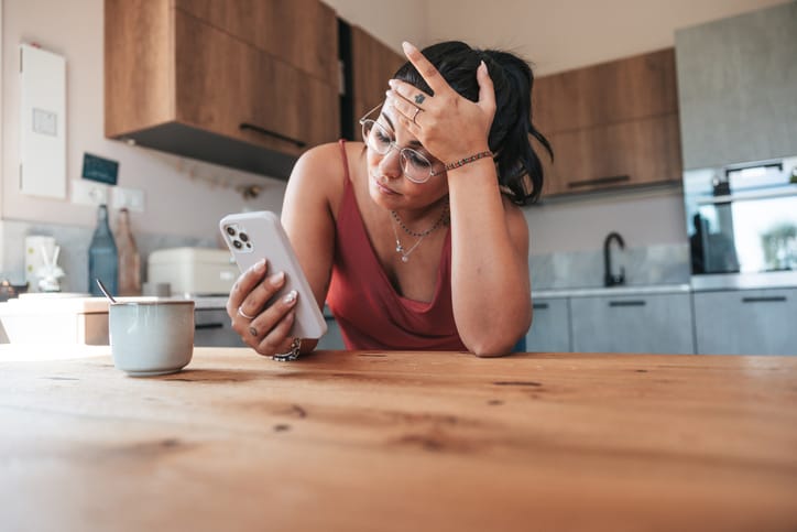 exhausted woman texting in kitchen
