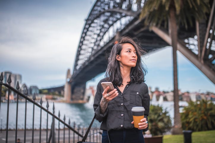 woman texting outdoor with coffee