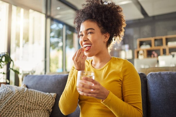 woman smiling while taking vitamin