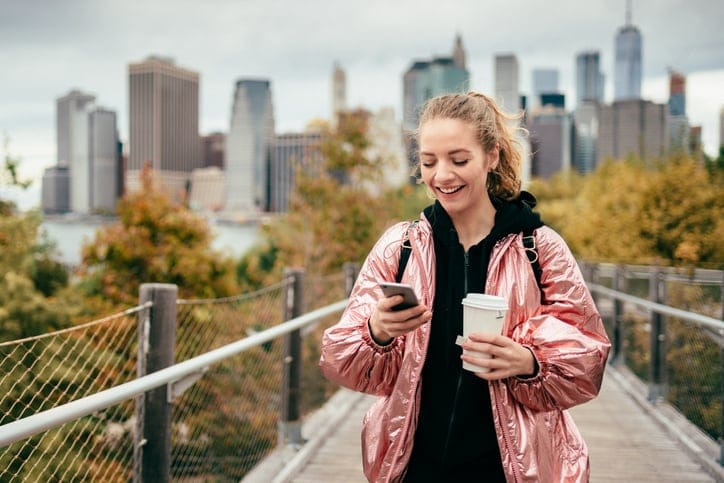 young woman texting while walking in NYC