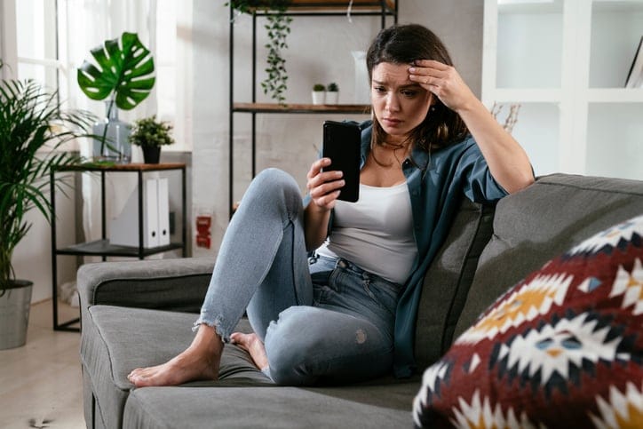 distressed woman reading texts on smartphone
