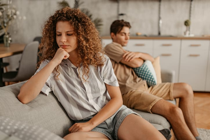 Unhappy couple arguing on couch.