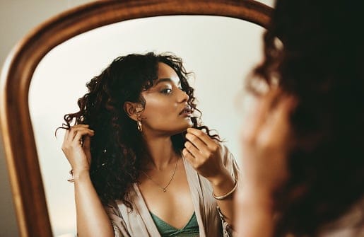 woman applying lipstick in mirror