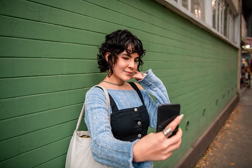 smiling woman taking selfie outside