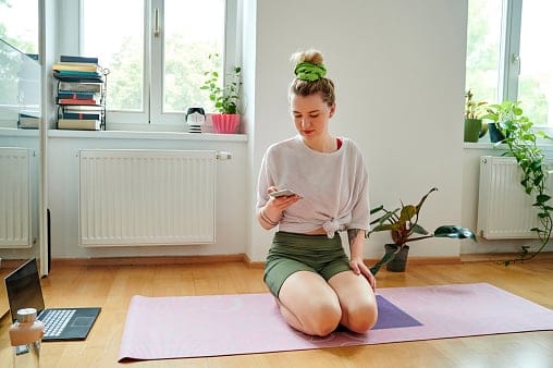 Woman texting on her yoga mat.